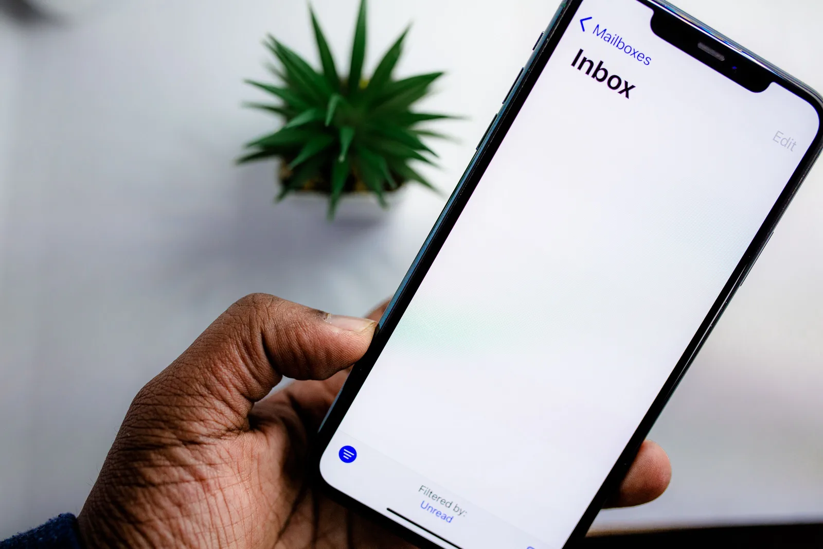 A close-up view of a smartphone screen displaying the email inbox, held by an adult's hand. Flooring Bid Follow Up Emails: Timing, Questions, and Stop Rules